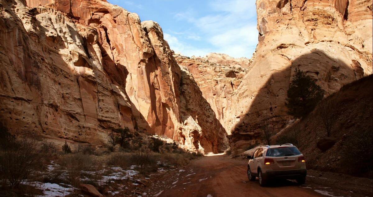 Car driving through a canyon landscape in the United States, symbolizing U.S. travel and tourism.