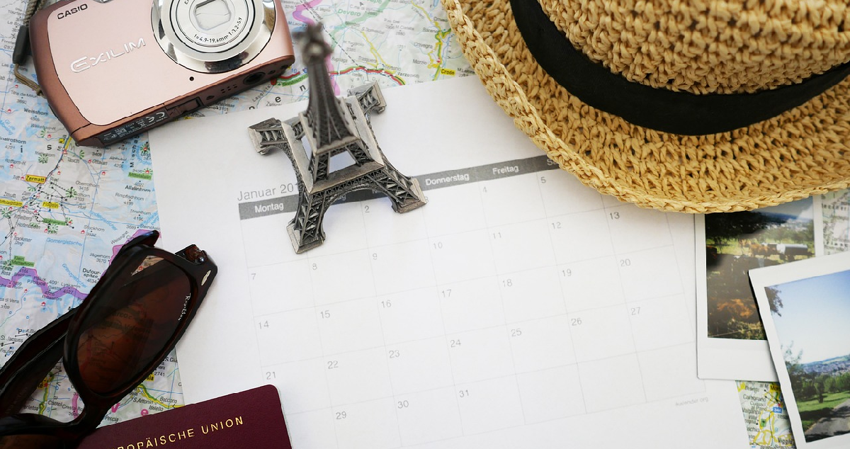 Travel planning flat lay with a calendar and other travel items around it