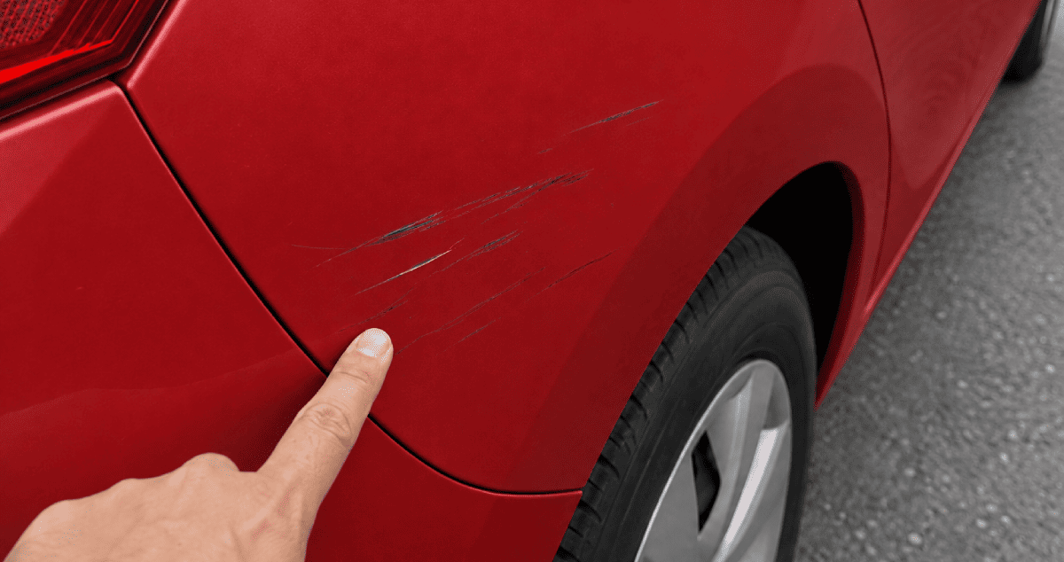 Finger pointing at a scratched car